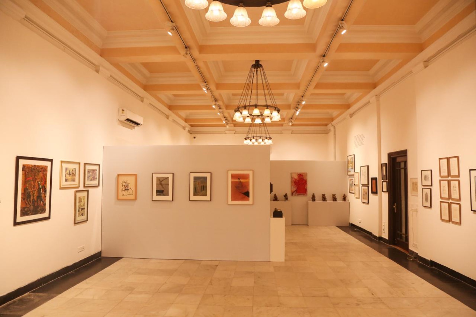 The main hall at Bikaner House: chandeliers over walls of modern Indian paintings.