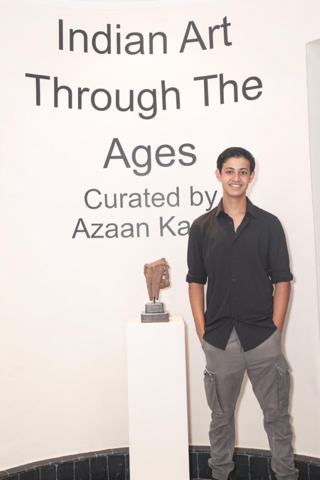 Azaan Karan beside the title wall of Indian Art Through the Ages at Bikaner House.